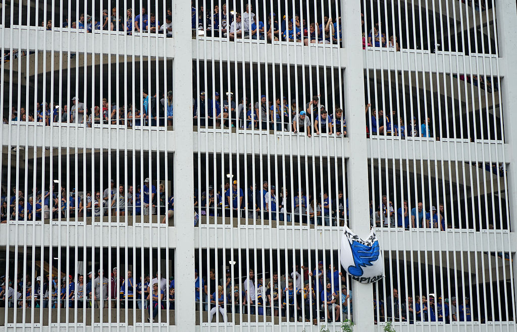 Fans peer through the slats of a parking garage